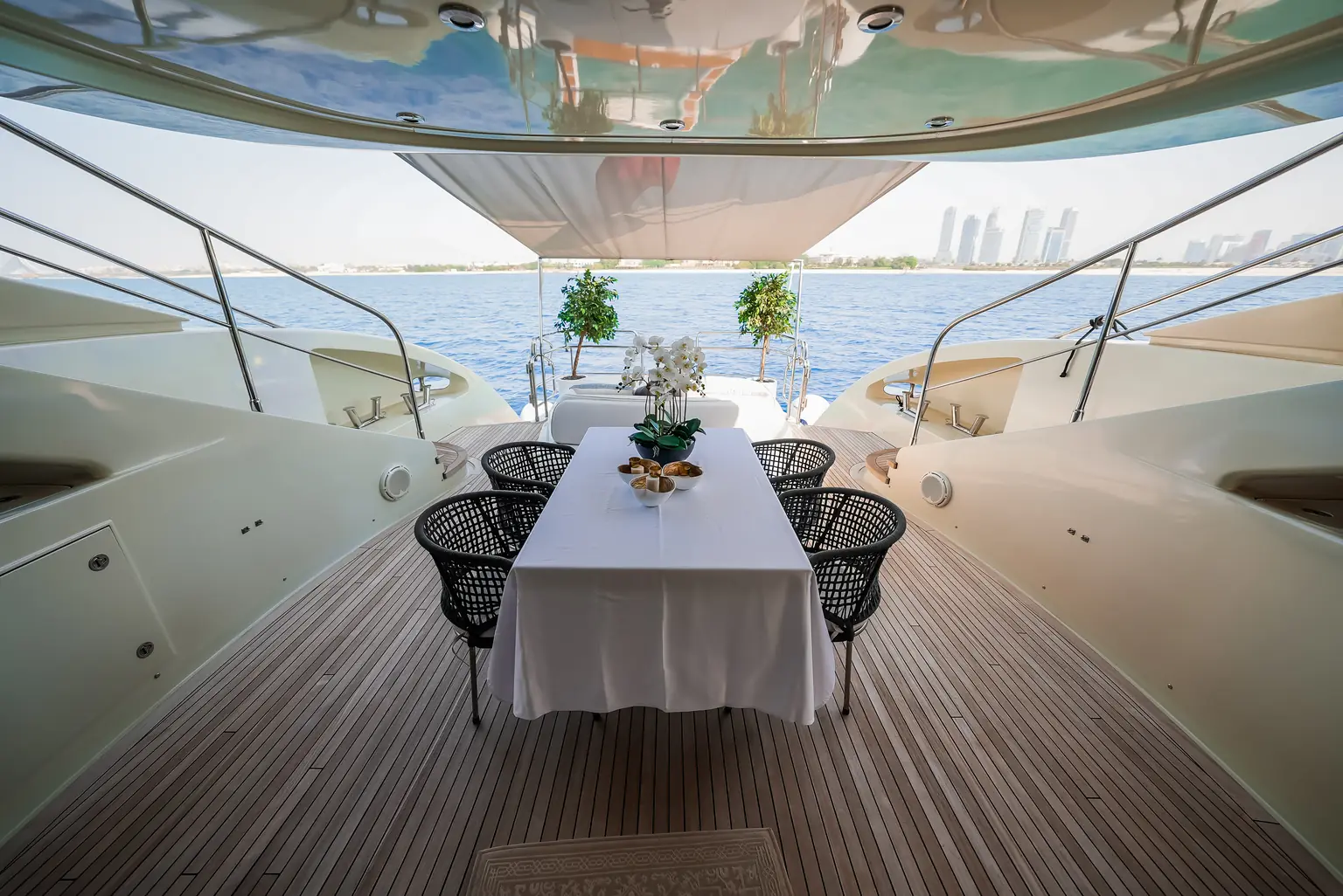 Aft deck dining table laid for guests, open to the sea on three sides